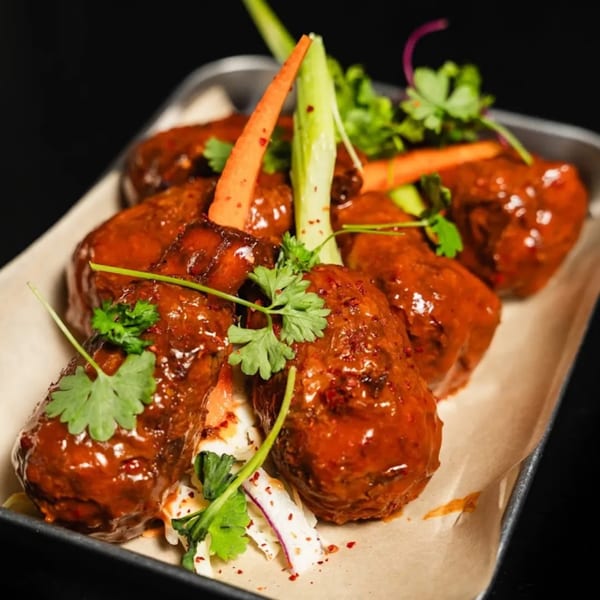 Vegan BBQ ribs with fresh cilantro, carrots, and green onions on a metal tray.